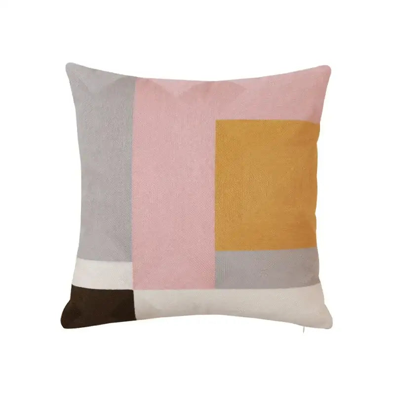 A modern geometric embroidery pillow cover featuring pink, mustard yellow, gray, cream, and dark brown fabric blocks