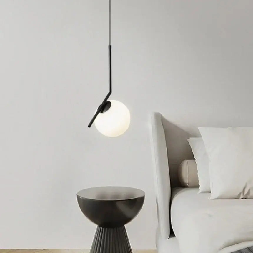 Minimalist black glass pendant light with frosted globe and sleek metal arm for bedroom bedside chandeliers