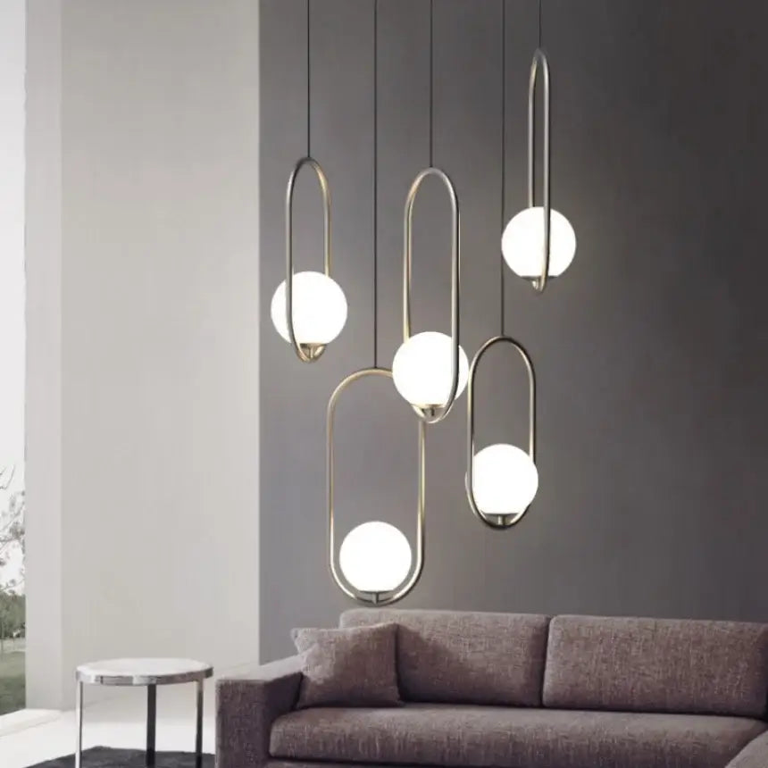 Modern geometric glass pendant lights featuring sleek curved metallic frames and white spherical shades for bedroom bedside