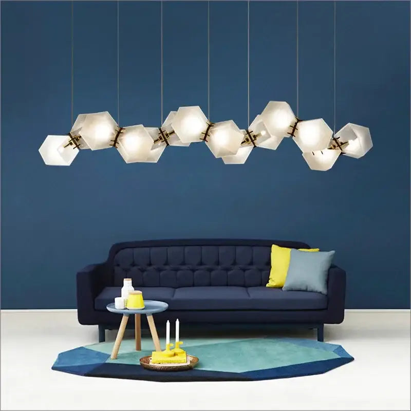 Modern white hexagonal e14 led glass pendant light with brass accents hanging above a navy blue sofa