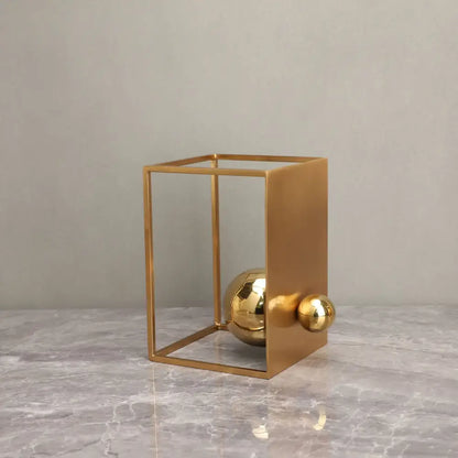 Modern geometric gold decorative figurines featuring a minimalist gold-toned cube frame with polished spheres