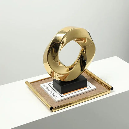 Modern geometric gold hollowed home decor sculpture with smooth reflective surface and intertwined loop design by decorbites