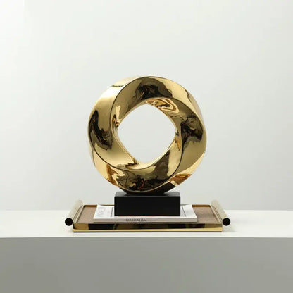 Shiny gold metallic geometric gold hollowed sculpture with twisted interlocking rings for modern home decor