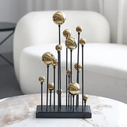 Modern abstract metal sculpture featuring multiple polished geometric golden ball spheres on slender black rods