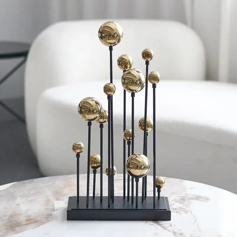 Modern abstract metal sculpture featuring multiple polished geometric golden ball spheres on slender black rods