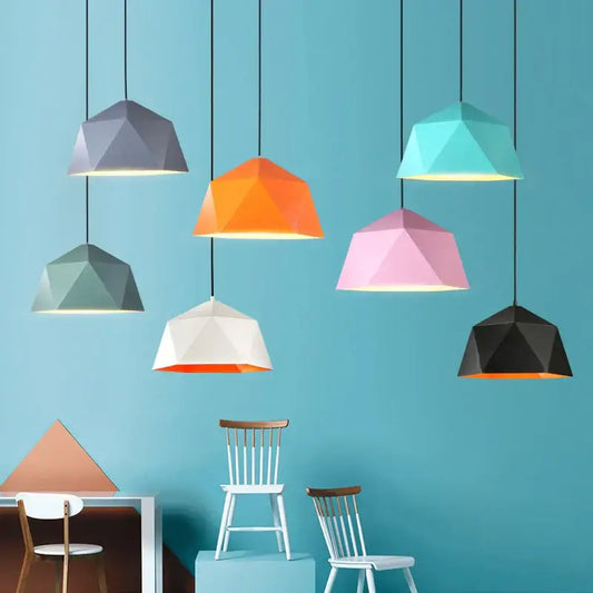 Modern geometric iron diamond pendant lights in pastel and vibrant hues hang from black cords against teal wall