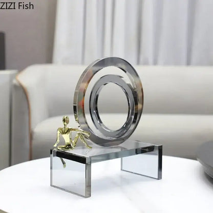A modern geometric ring chair sculpture with polished chrome ring and gold figurine on a transparent ring chair base