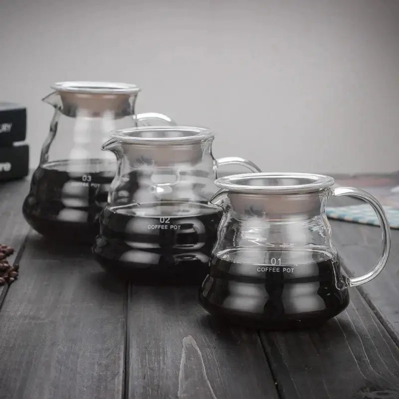 Modern glass coffee pot with stainless steel lid and handle featuring volume indicators for kitchen dining use