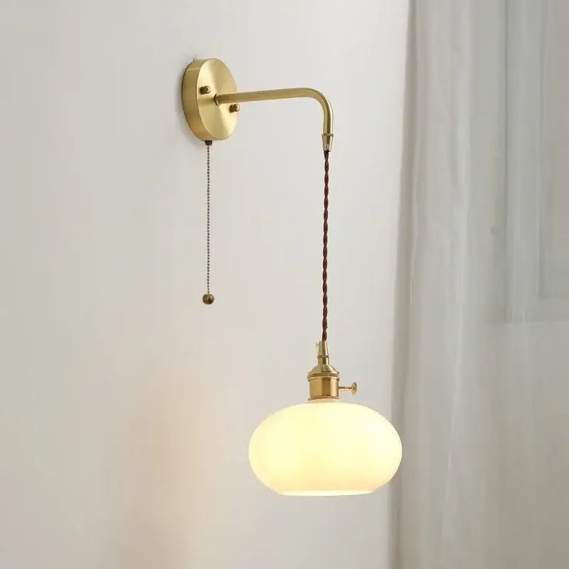 Modern glass copper led wall light with gold-toned brass sconce, curved arm, brown braided cord, and oval opal glass shade