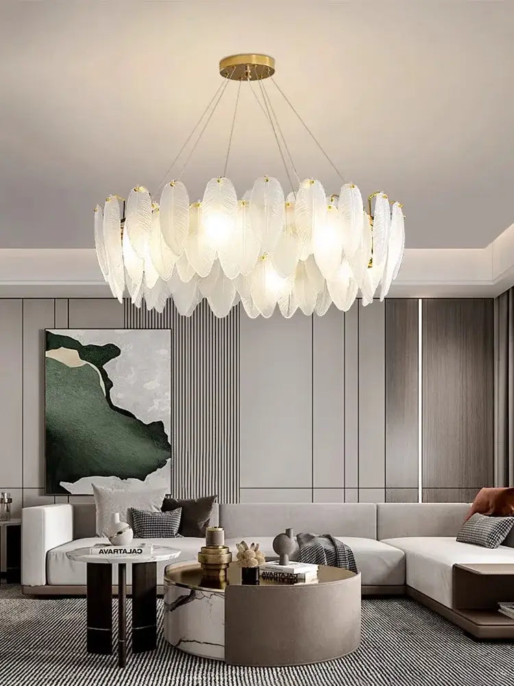 White feather-shaped glass feather chandelier with gold brass accents hanging from ceiling for living room lighting