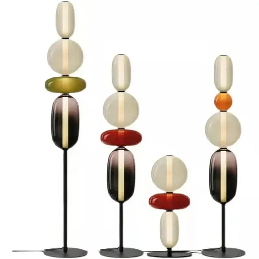 Set of three modern glass floor lamps with stacked orbs in cream amber and burgundy on black metal stands with led light
