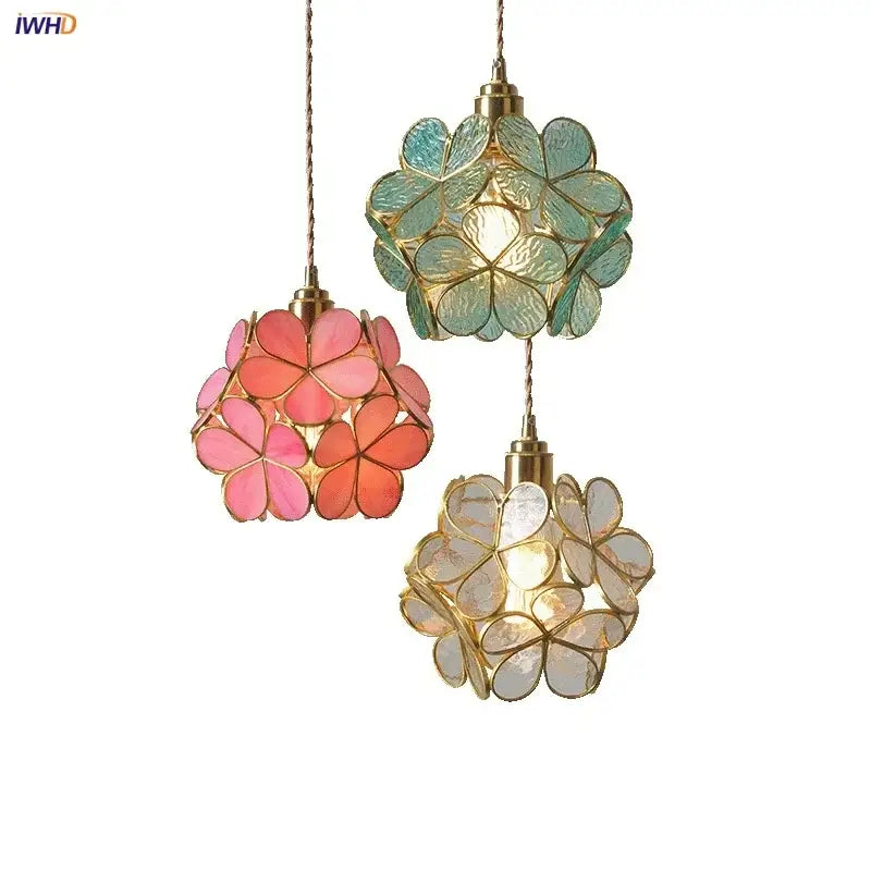 Three hanging pendant lights with glass flower led petals in pink teal and clear suspended by gold chains for dining room