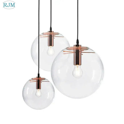 Set of three clear glass globe chrome pendant lights with copper fixtures and exposed bulbs for dining room use