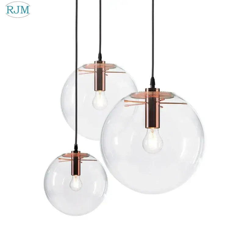 Set of three clear glass globe chrome pendant light fixtures with copper-toned metal for modern dining room lighting
