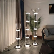 Three modern glass led floor lamps with stacked cylindrical sections and glowing white led rings for living room use
