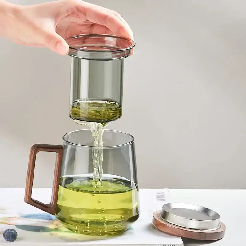 Modern decorbites glass tea cup with wooden handle and removable metal strainer filled with green tea for kitchen use