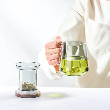 Modern glass tea cup by decorbites with clear glass body and wood handle filled with green tea for kitchen use