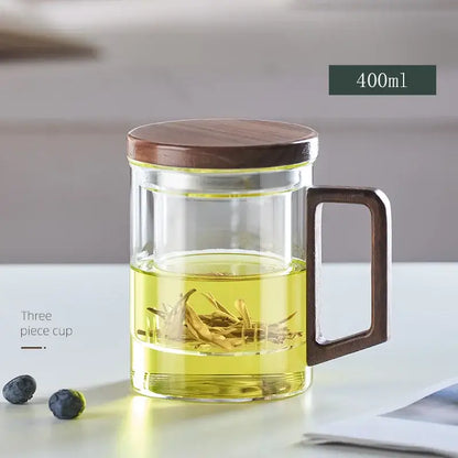 Modern decorbites glass tea cup with wood handle and lid filled with golden tea leaves steeping in amber liquid for kitchen drinking