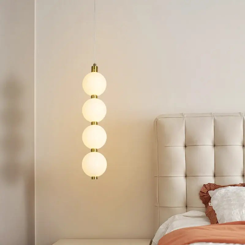 Modern pendant light with four frosted glass spheres and plated gold-toned surface as a dining room focal point