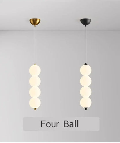 Two minimalist pendant lights with four frosted glass spheres and plated gold-toned surface as dining room focal point
