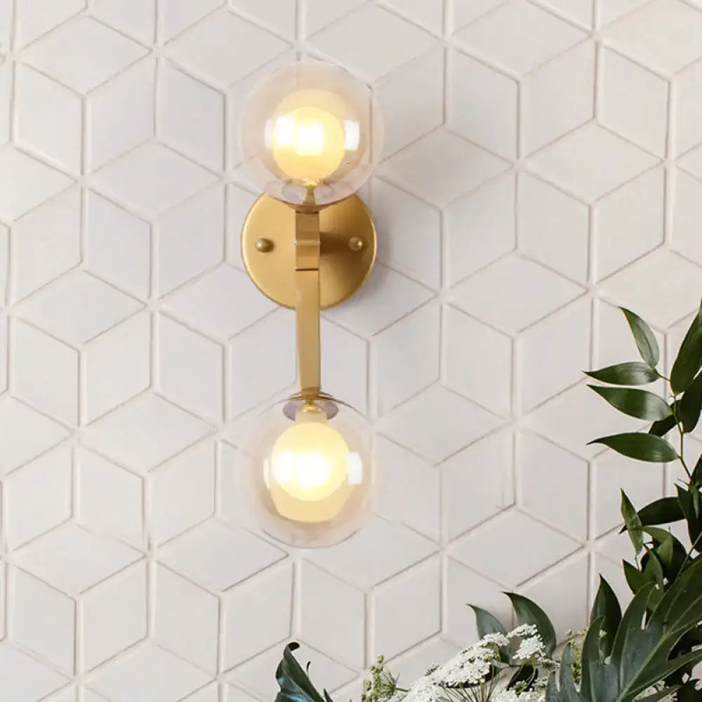 Modern gold amber glass wall light fixture with two spherical shades emitting warm glow for bedroom accent