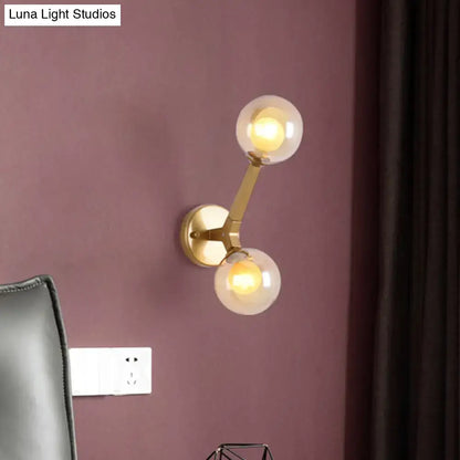 Modern gold wall light fixture with two amber glass spherical bulbs for bedroom accent lighting