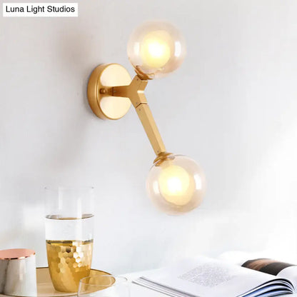 Modern gold wall light fixture with two amber glass globes designed as a bedroom accent light fixture