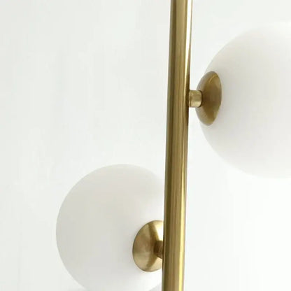 Modern brass-finished floor lamp with frosted white glass ball led shades complementing gold and black pendant lights