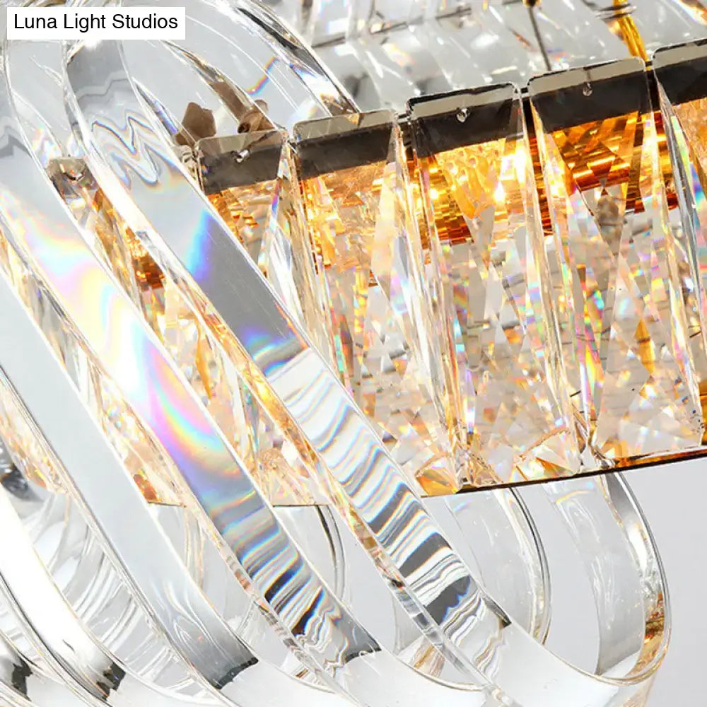 Modern gold and clear crystal oval pendant light featuring faceted crystals and warm amber lighting for dining room