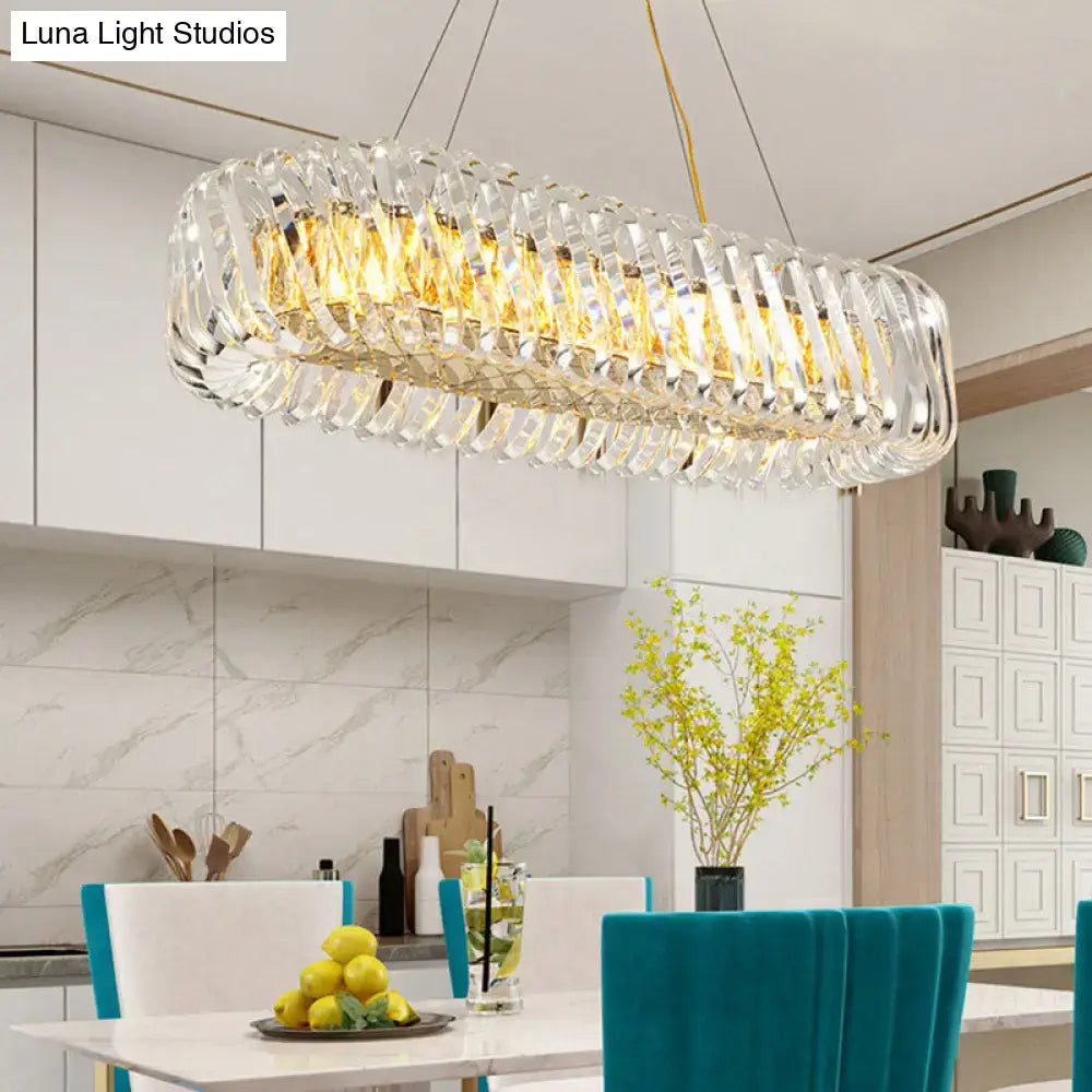 Modern gold and clear crystal oval pendant light with faceted design and warm golden lighting for dining room