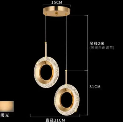 Modern gold and crystal oval bedside pendant light with two circular crystal-encrusted shades on adjustable cords