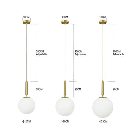 Three modern gold globe pendant lights with frosted glass spheres and brass accents in three sizes for kitchen island