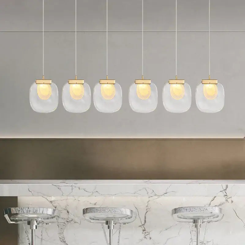 Set of five modern gold and glass pendant lights with clear glass shades for dining room decor and lighting
