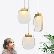 Three modern gold and glass pendant lights with oval glass pendant shades emitting warm glow for dining room