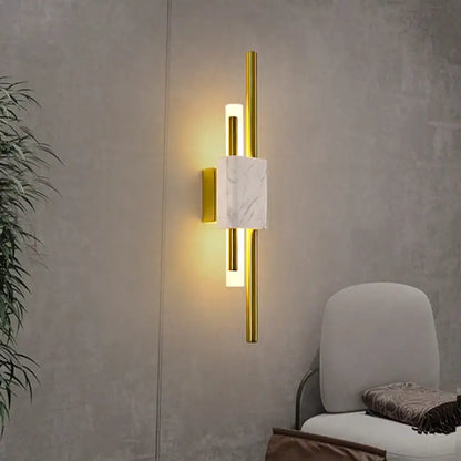 Modern gold wall lamp with rectangular white marble accent and two vertical cylindrical lights for bedroom sconce