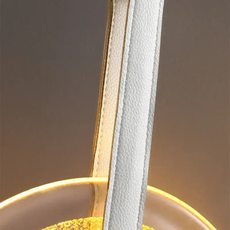 White leather strap with gold-toned stitching and trim on modern gold and white circular glass led chandelier by decorbites
