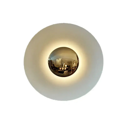 A sleek modern led ufo wall sconce with matte white outer ring and gold-toned central sphere for bedside decor