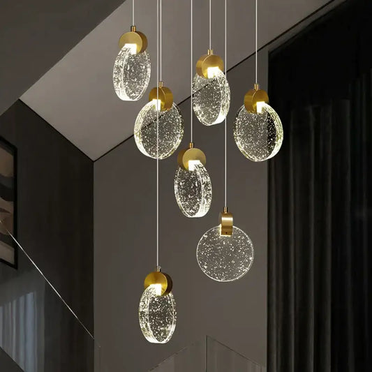 Modern gold attic crystal chandelier with clear bubble-filled glass discs hanging from thin cords for dining room lighting