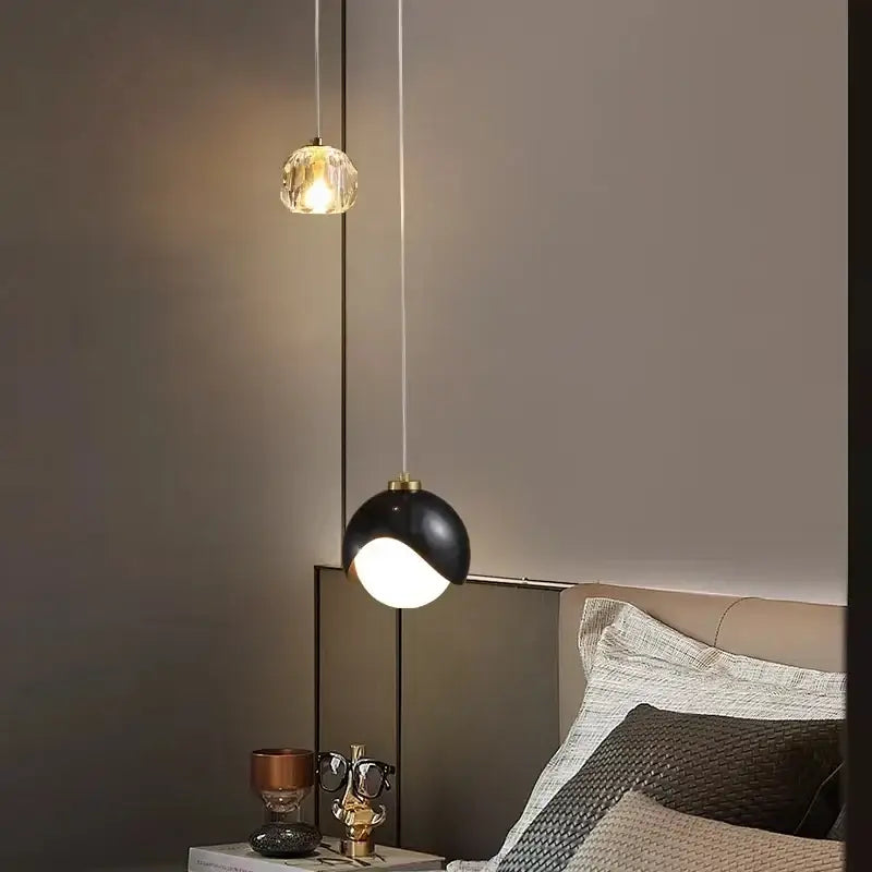 Two modern linear pendant lights feature a gold faceted crystal globe and a black matte dome for dining room use