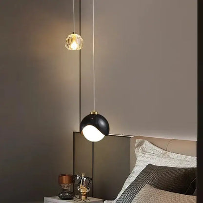 Two modern linear pendant lights feature a gold faceted crystal globe and a black matte dome for dining room use