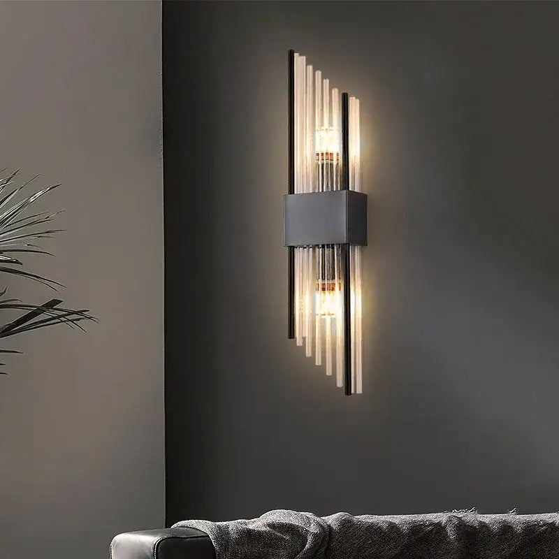 Modern gold and black crystal wall lamp with sleek rectangular metal base and vertical glass rods emitting warm light
