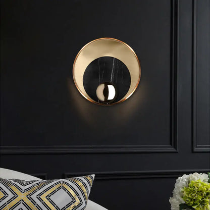 Modern gold and black marble wall sconce with peacock tail feather design featuring a reflective inner surface