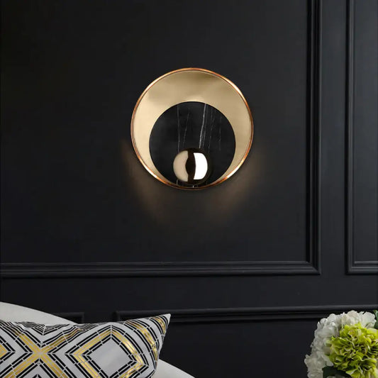 Modern gold and black marble wall sconce with peacock tail feather design featuring a reflective inner surface