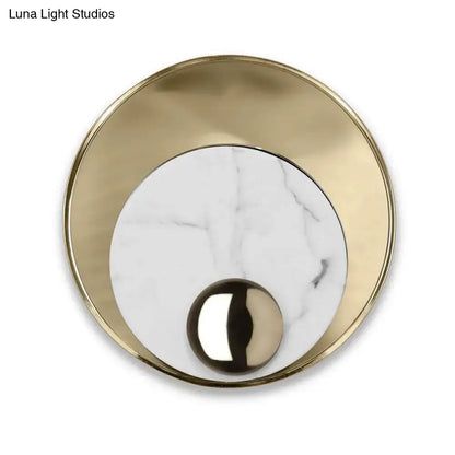 Modern gold and black marble wall sconce with brushed gold frame white marble center and peacock tail feather design