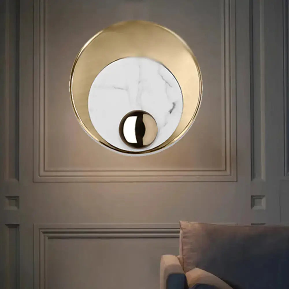 Modern gold wall sconce with white marble center and black sphere featuring peacock tail feather design for living room