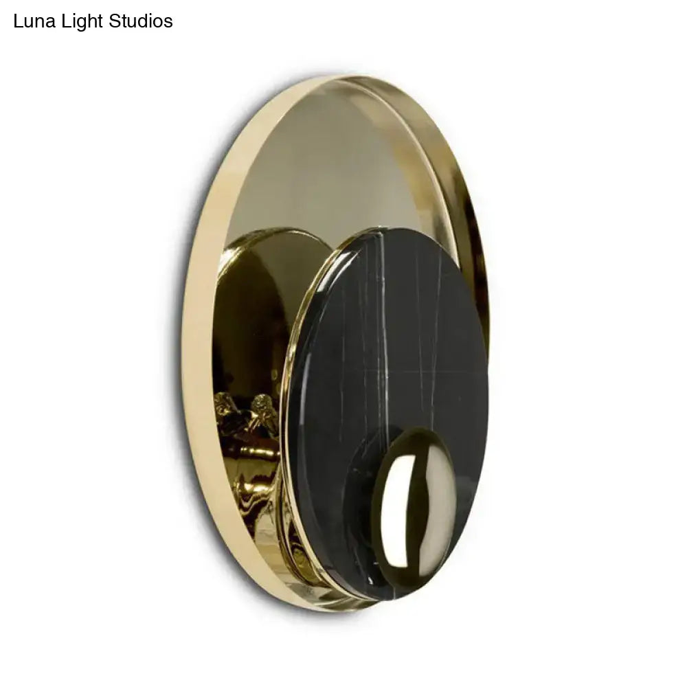 Gold-toned circular wall sconce with a black marble-like center and polished metallic finish.