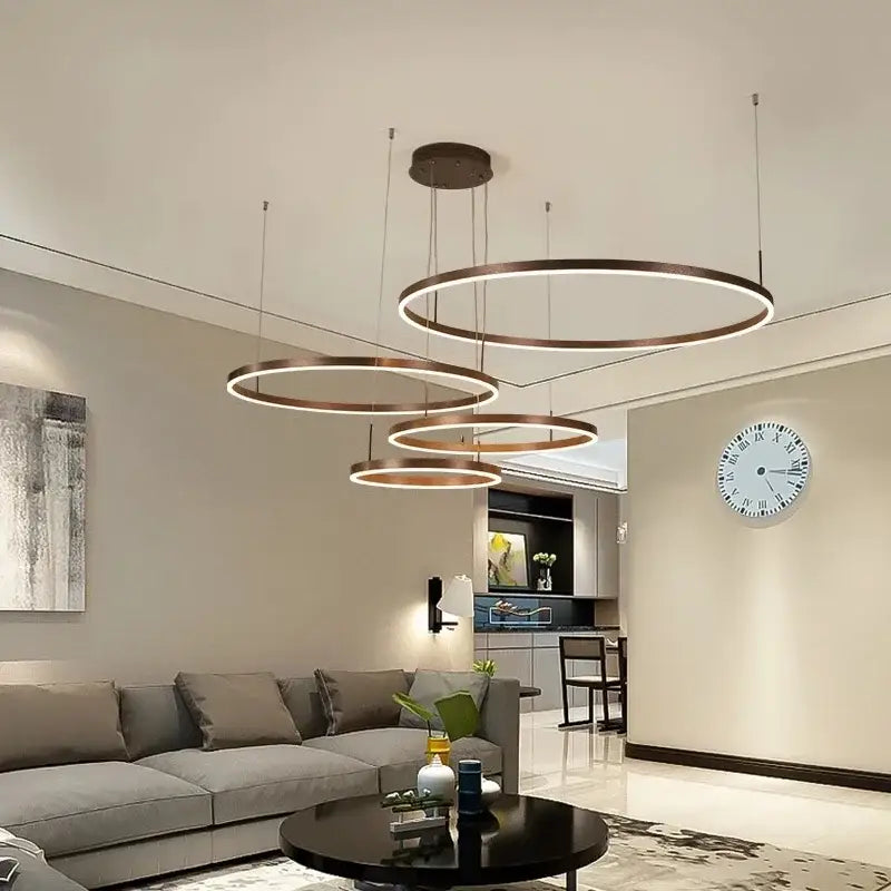 Modern gold and black bronze pendant light with illuminated circular rings for dining rooms in contemporary interiors