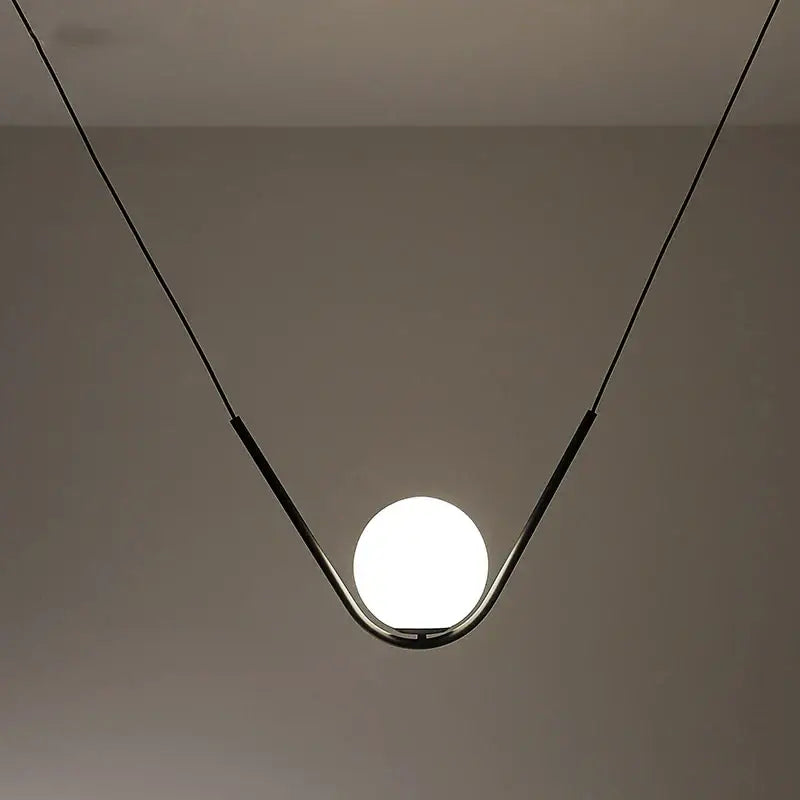 Minimalist pendant light with a sleek black metal frame and spherical glass bulb from decorbites golden black perle collection