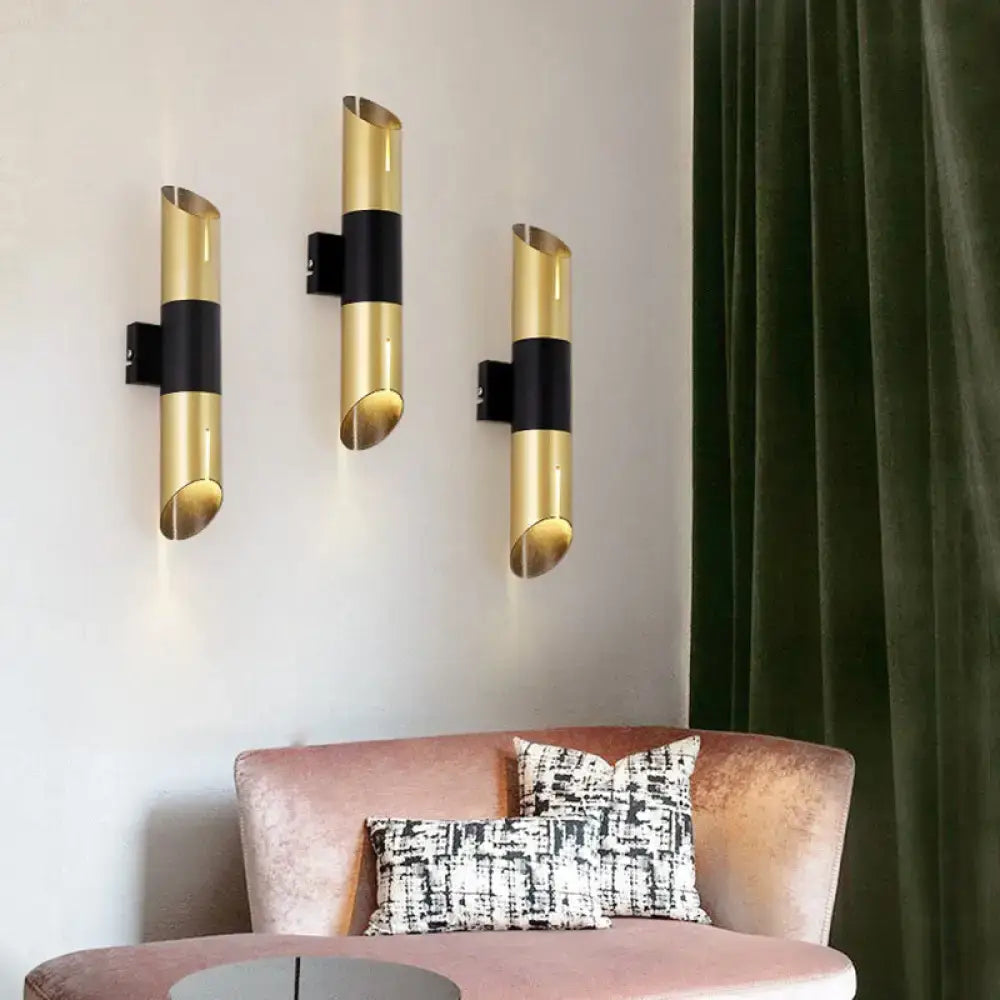 Three modern gold and black rotatable cylinder wall sconces with sleek curved design for bedroom lighting