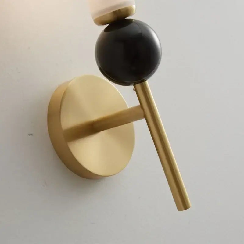 Modern wall lamp with gold-toned copper base, sleek black accent, and opaque glass shade for living room decor